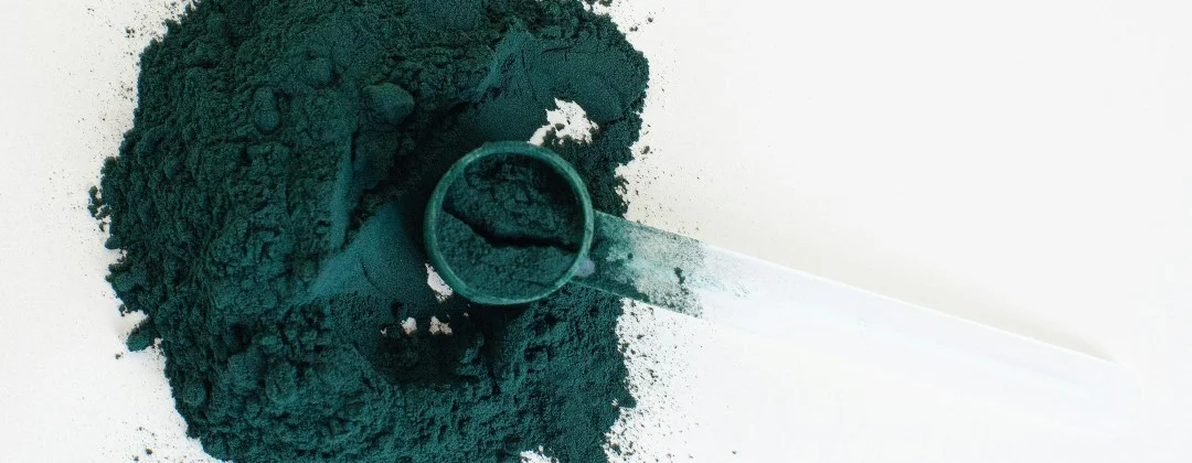Spirulina als Pulver mit einem Plastiklöffel